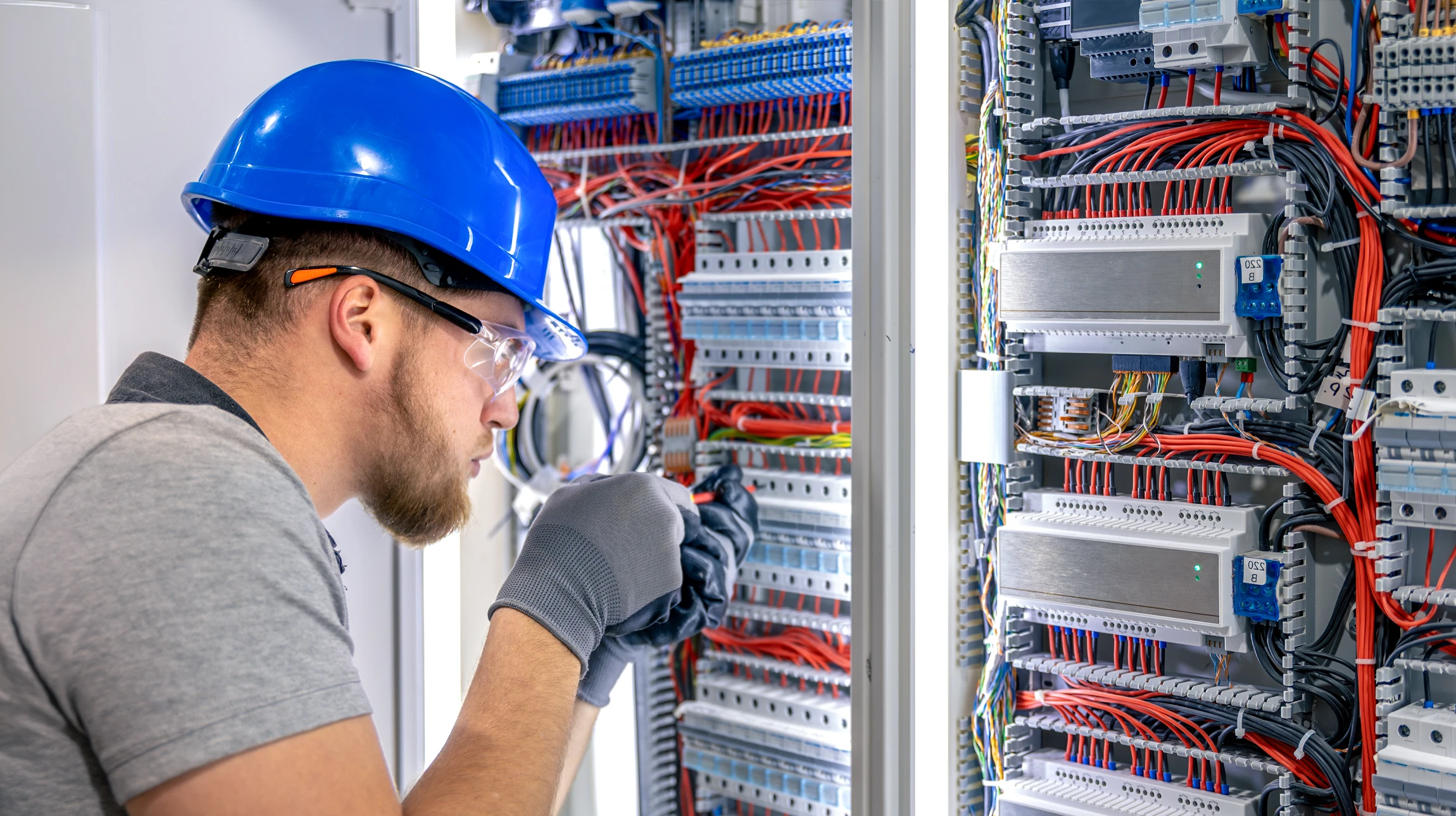 Électricien en combinaison bleue et casque orange travaillant sur installation électrique murale